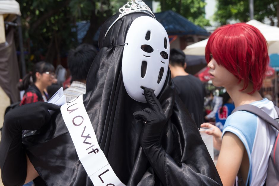 Two people in creative costumes at an outdoor cosplay event.