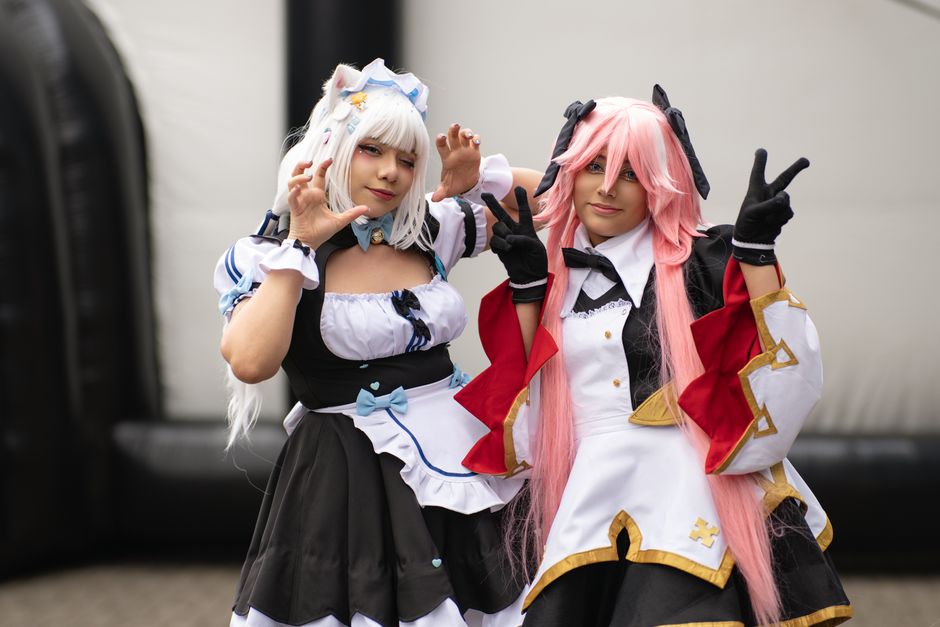 Two people in creative costumes at an outdoor cosplay event.