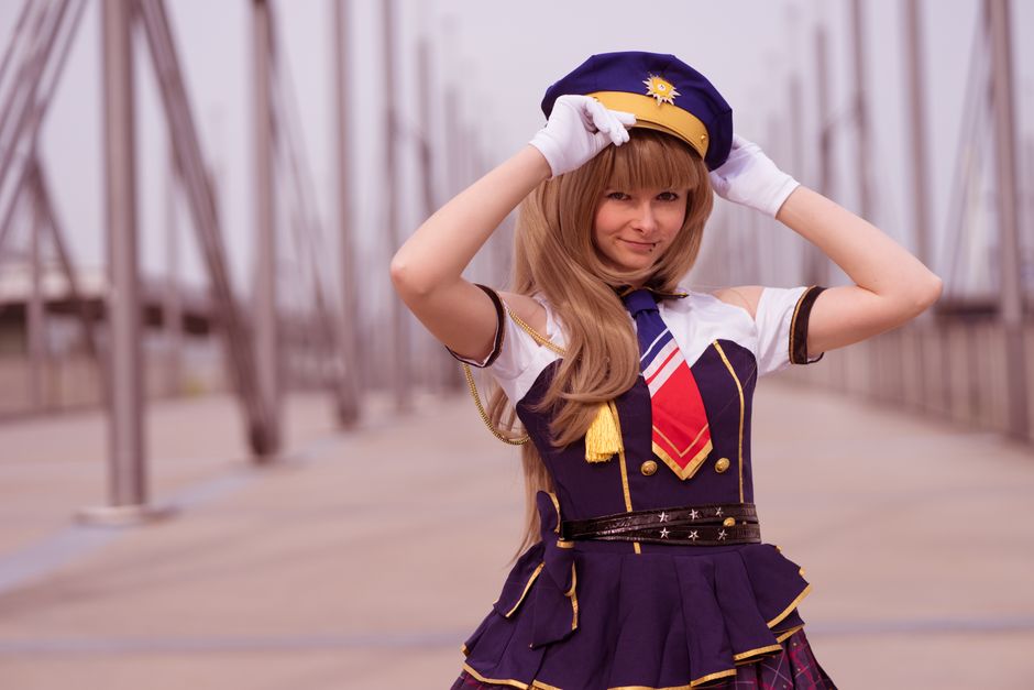 A vibrant cosplay portrait of a young adult in costume posing with a peace sign outdoors.